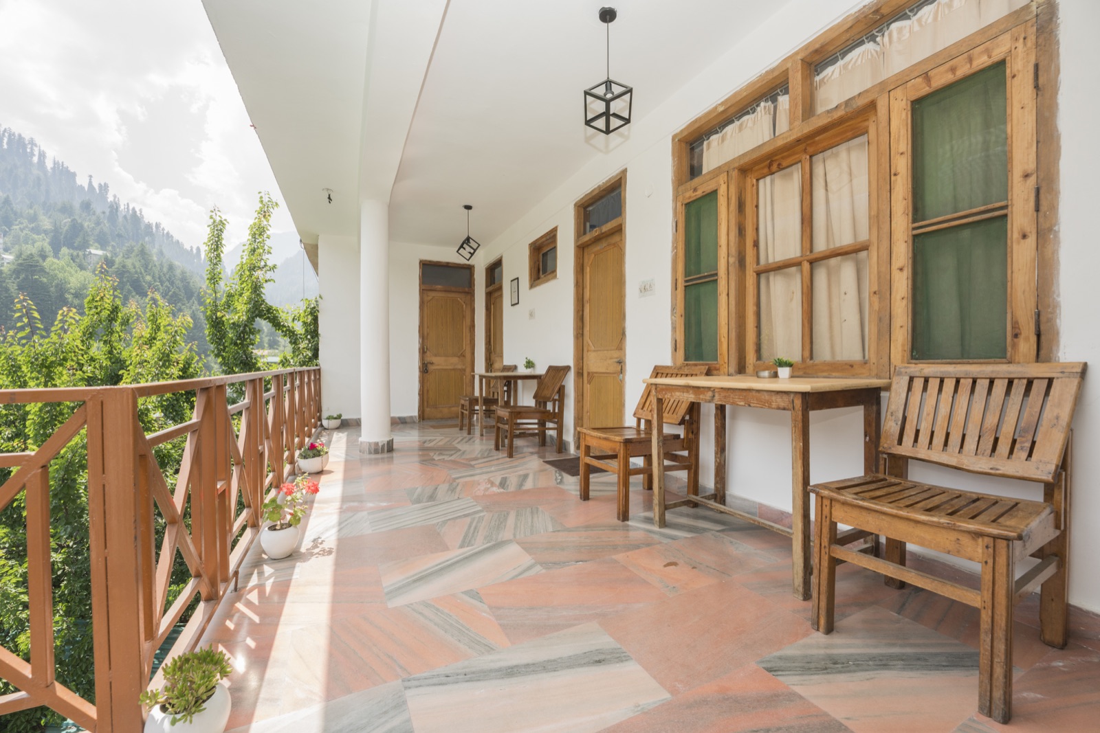 Covered corridor with potted plants and a mountain view