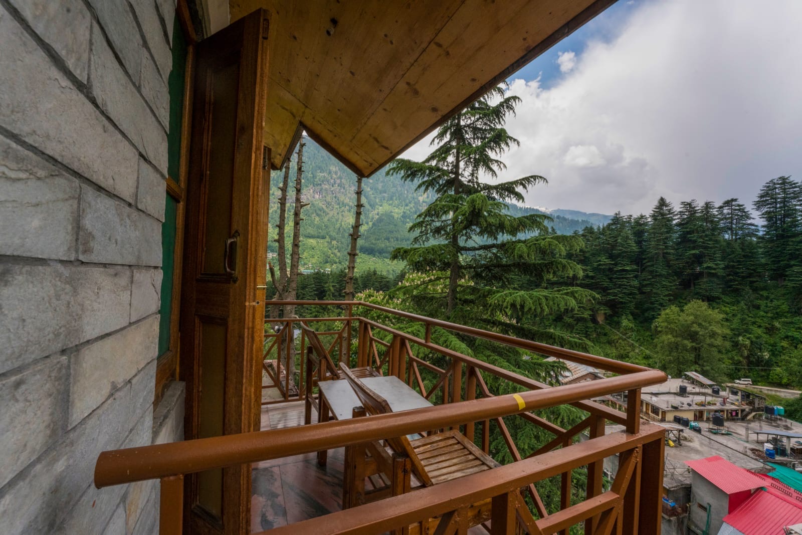 View from the room out through the balcony doorway to pine trees and mountains