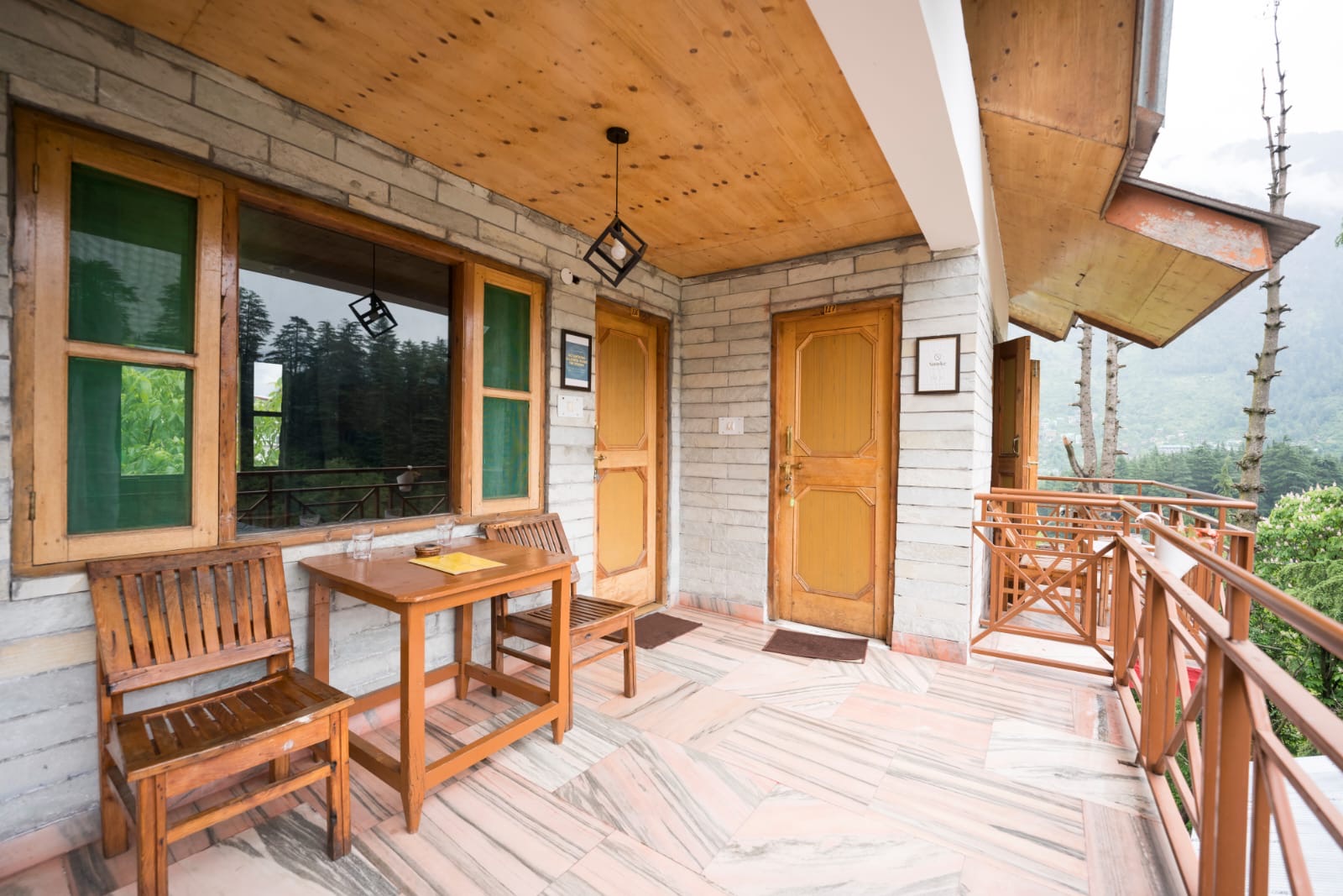 The balcony itself, a table and two chairs, forested hillside beyond